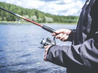 Angler holding fishing rod by lake