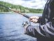 Angler holding fishing rod by lake