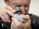 Person examining rough mineral with jeweler's loupe